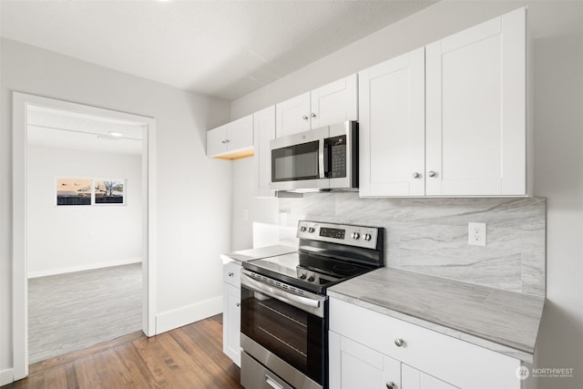 kitchen featuring stainless steel appliances, white cabinetry, tasteful backsplash, and hardwood / wood-style flooring