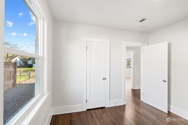 unfurnished bedroom featuring multiple windows and dark wood-type flooring