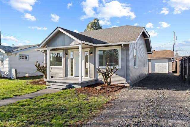 bungalow-style home featuring a garage, a porch, and an outdoor structure