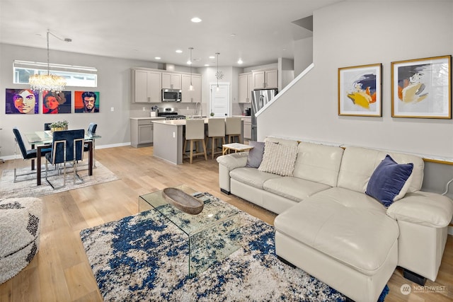 living room featuring sink, an inviting chandelier, and light wood-type flooring