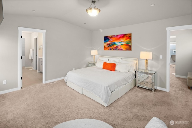 carpeted bedroom with connected bathroom and lofted ceiling