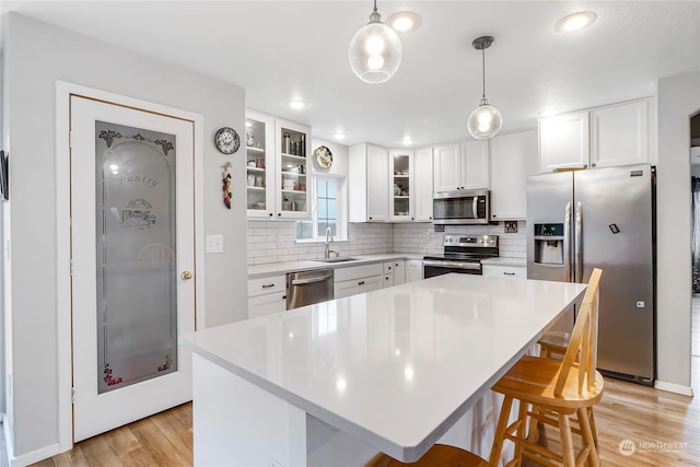 kitchen featuring a kitchen breakfast bar, white cabinetry, hanging light fixtures, and appliances with stainless steel finishes