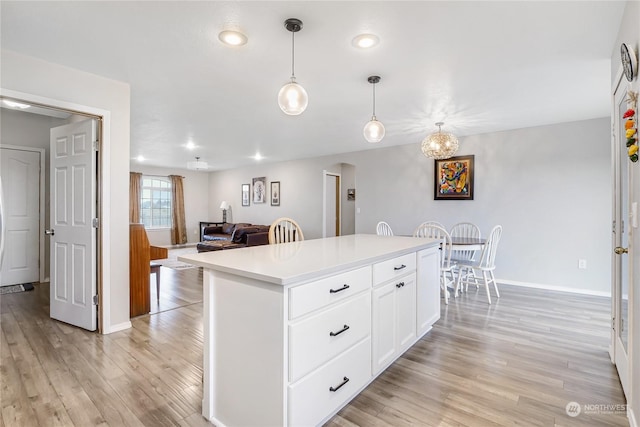 kitchen with a center island, white cabinetry, light hardwood / wood-style floors, and hanging light fixtures