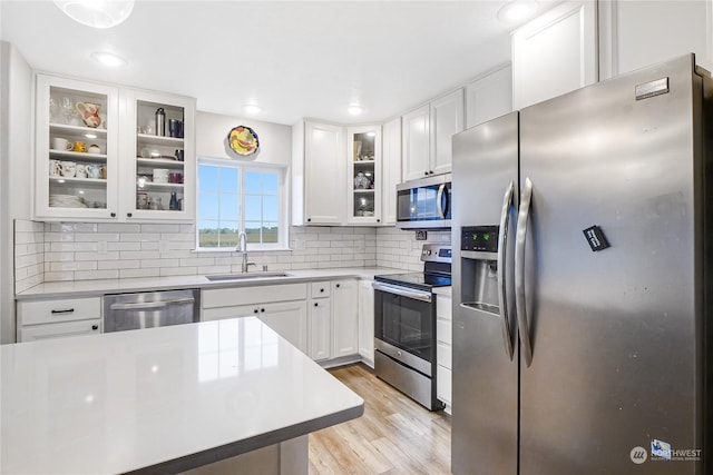 kitchen featuring light hardwood / wood-style flooring, backsplash, white cabinetry, appliances with stainless steel finishes, and sink