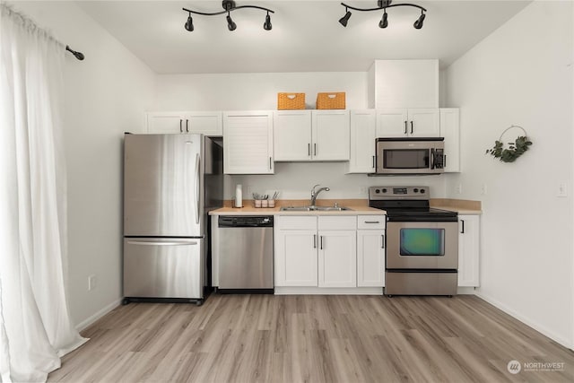 kitchen with light hardwood / wood-style floors, sink, white cabinetry, and appliances with stainless steel finishes