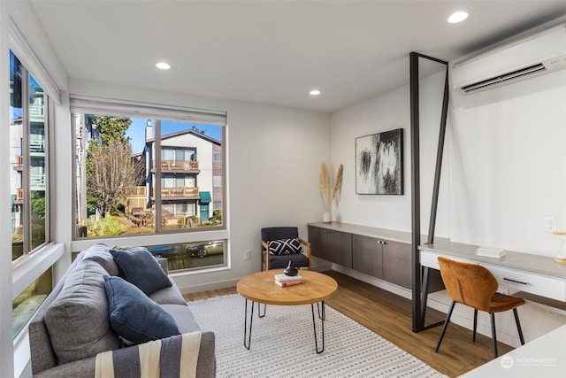 sitting room with light wood-type flooring and an AC wall unit