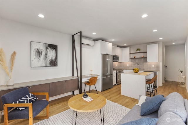 living room with sink, a wall mounted air conditioner, and light hardwood / wood-style flooring