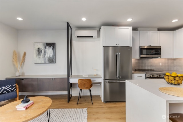 kitchen with white cabinets, an AC wall unit, appliances with stainless steel finishes, and tasteful backsplash