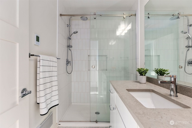 bathroom with a shower with shower door and vanity