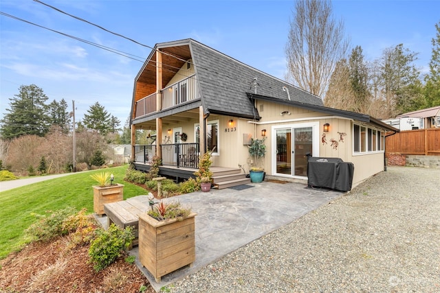 back of property featuring a lawn, a balcony, and a patio