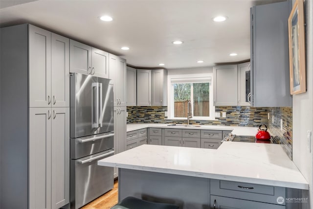 kitchen featuring stainless steel appliances, sink, gray cabinetry, and kitchen peninsula