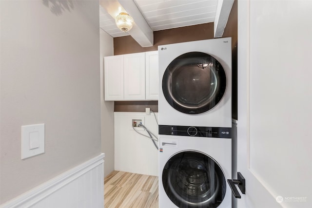 washroom featuring stacked washing maching and dryer, cabinets, and light hardwood / wood-style floors