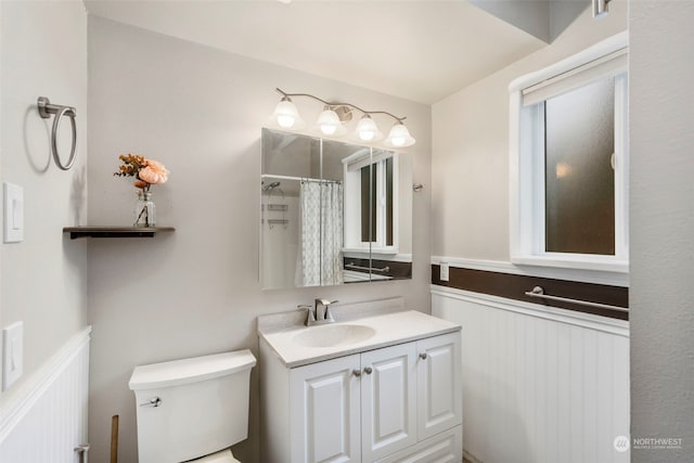 bathroom with curtained shower, vanity, and toilet