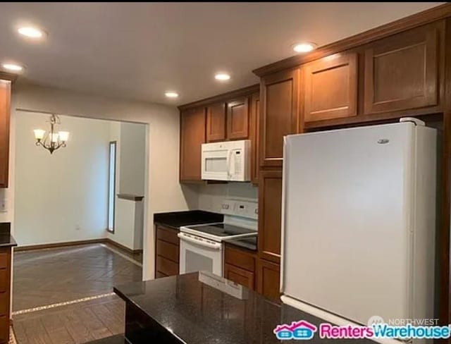 kitchen with white appliances, an inviting chandelier, dark parquet floors, and hanging light fixtures