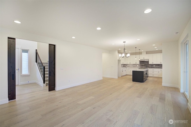 unfurnished living room with a chandelier and light hardwood / wood-style floors