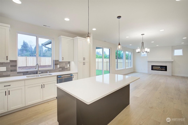 kitchen featuring a center island, white cabinetry, tasteful backsplash, sink, and stainless steel dishwasher