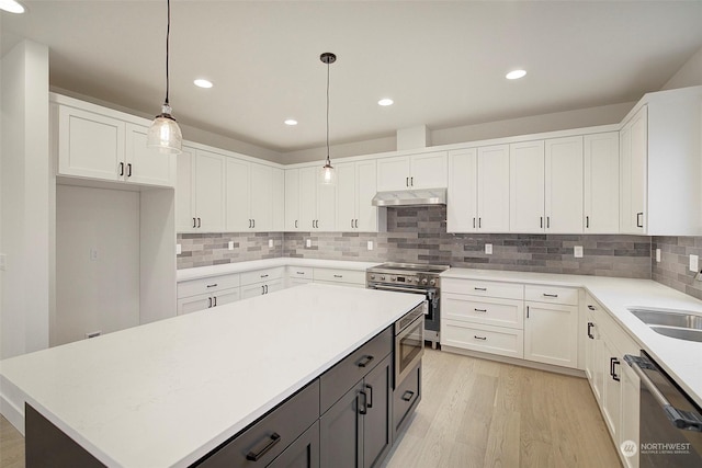 kitchen featuring a center island, hanging light fixtures, light wood-type flooring, stainless steel appliances, and white cabinets