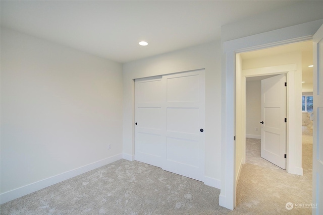 unfurnished bedroom with a closet and light colored carpet