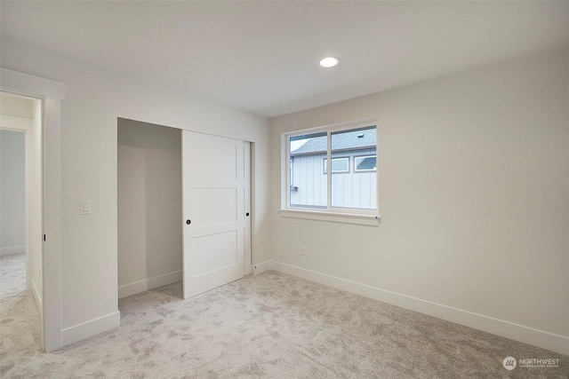 unfurnished bedroom featuring light colored carpet and a closet