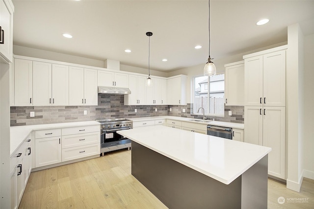 kitchen featuring a kitchen island, sink, white cabinetry, hanging light fixtures, and stainless steel appliances