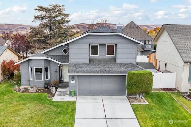 view of front facade featuring a mountain view, a front yard, and a garage