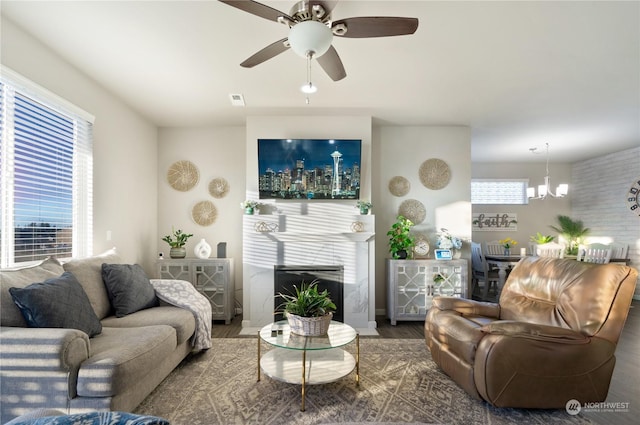 living room featuring ceiling fan with notable chandelier, wood-type flooring, and a premium fireplace