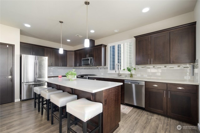 kitchen featuring dark brown cabinetry, sink, a center island, hanging light fixtures, and stainless steel appliances