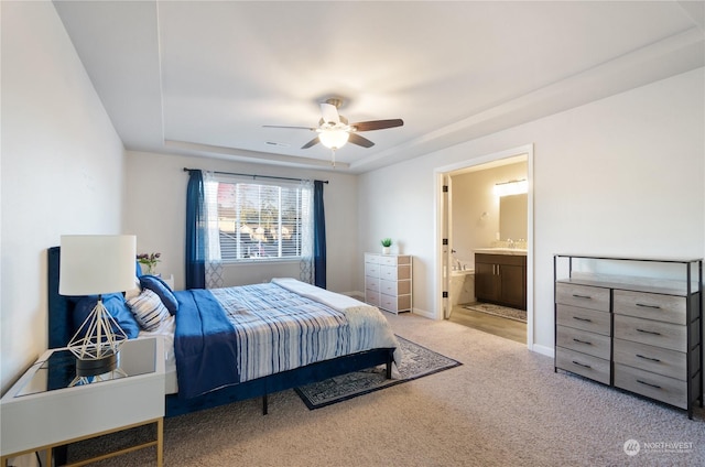 carpeted bedroom with connected bathroom, a tray ceiling, and ceiling fan