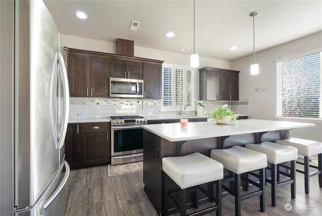 kitchen featuring stainless steel appliances, a center island, hanging light fixtures, and a breakfast bar area