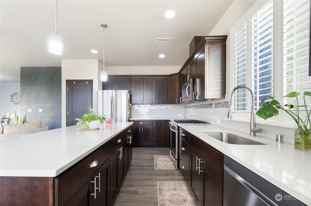 kitchen featuring sink, dark wood-type flooring, backsplash, hanging light fixtures, and stainless steel appliances