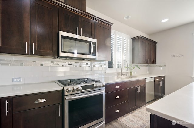 kitchen with appliances with stainless steel finishes, sink, dark brown cabinets, and backsplash