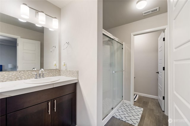 bathroom with vanity, decorative backsplash, wood-type flooring, and walk in shower