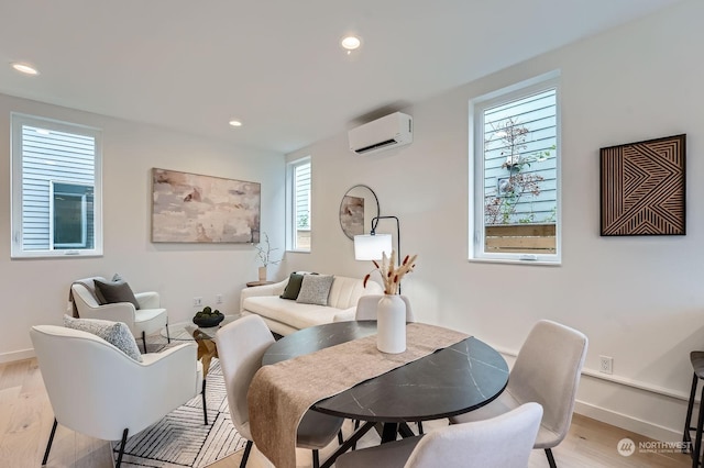 dining space featuring an AC wall unit and light hardwood / wood-style floors