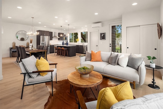 living room featuring light wood-type flooring, a wall mounted AC, and an inviting chandelier