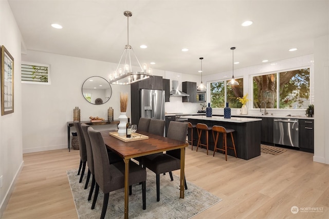 dining space with light wood-type flooring, sink, and an inviting chandelier