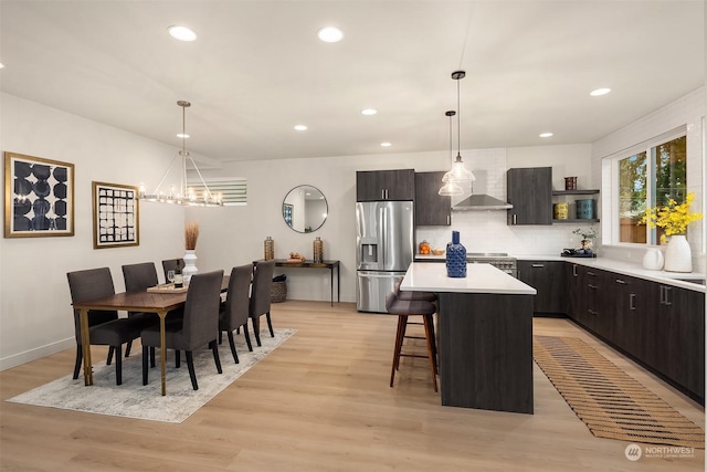 kitchen with light wood-type flooring, stainless steel appliances, hanging light fixtures, and a center island