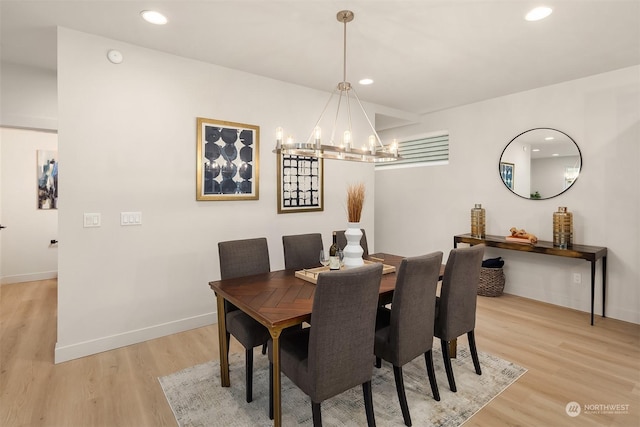 dining area with light wood-type flooring and a chandelier