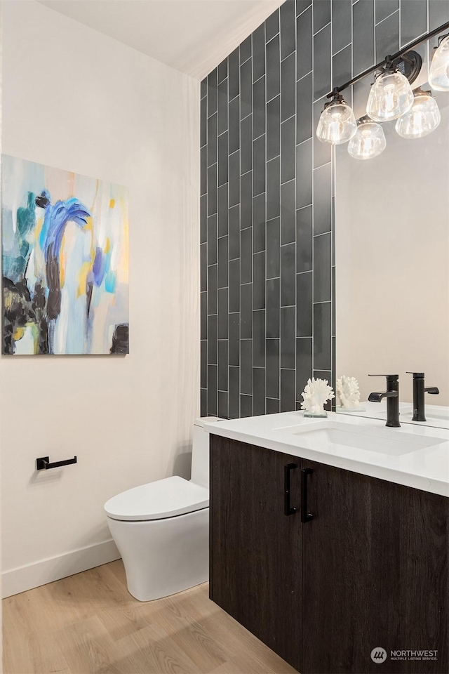 bathroom featuring wood-type flooring, toilet, vanity, and tile walls