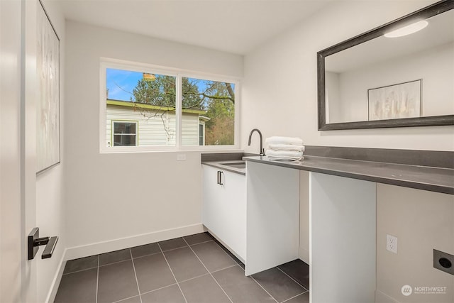 clothes washing area featuring electric dryer hookup, dark tile patterned floors, and sink