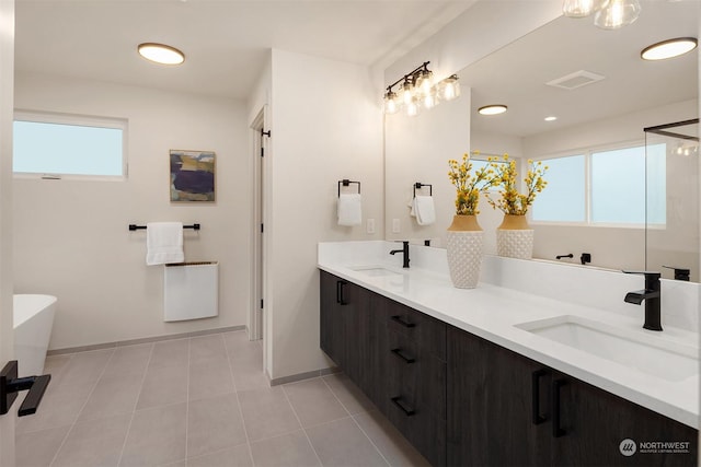 bathroom with tile patterned flooring, a healthy amount of sunlight, vanity, and a tub