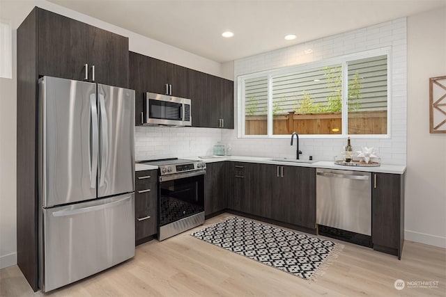 kitchen featuring backsplash, sink, dark brown cabinetry, light hardwood / wood-style flooring, and stainless steel appliances