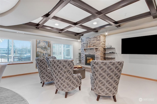 living room featuring beamed ceiling, coffered ceiling, and a stone fireplace