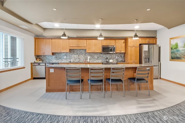 kitchen with an island with sink, appliances with stainless steel finishes, light stone countertops, and a breakfast bar