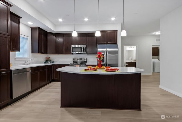 kitchen featuring pendant lighting, stainless steel appliances, light hardwood / wood-style floors, a kitchen island, and sink