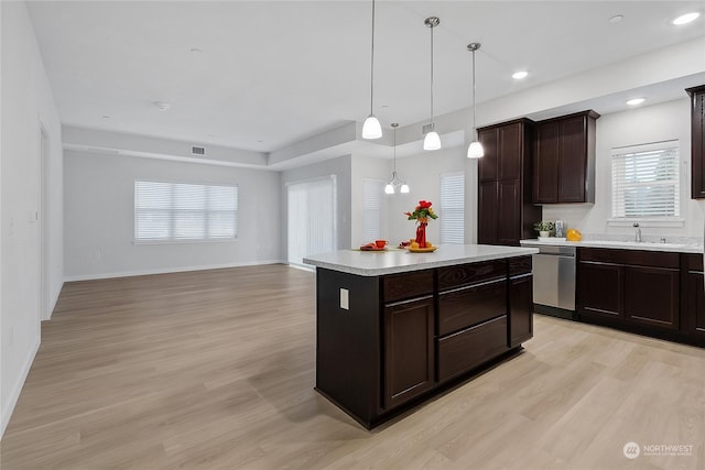 kitchen featuring light wood-type flooring, a kitchen island, dark brown cabinetry, decorative light fixtures, and stainless steel dishwasher