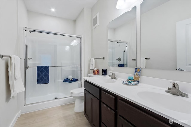 bathroom featuring wood-type flooring, vanity, a shower with shower door, and toilet