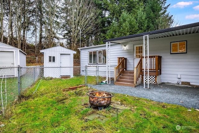 back of house featuring a storage unit and a fire pit