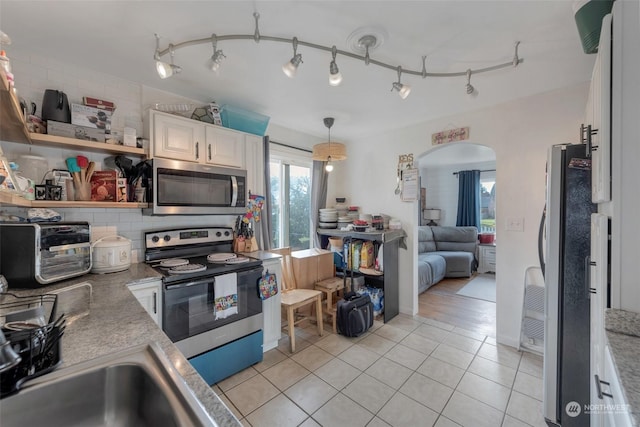 kitchen featuring decorative light fixtures, backsplash, white cabinetry, stainless steel appliances, and light tile patterned floors