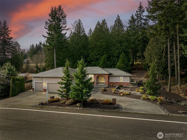 ranch-style house with a garage, concrete driveway, and brick siding