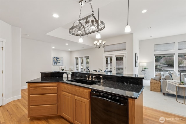 kitchen featuring light wood finished floors, open floor plan, a sink, an island with sink, and dishwasher